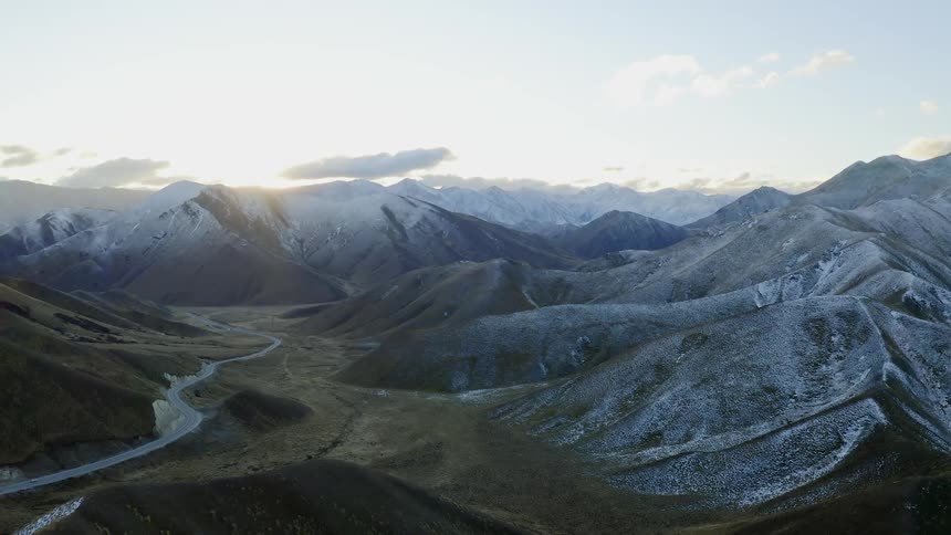 The mountain range has a road winding around the middle with vehicles traveling