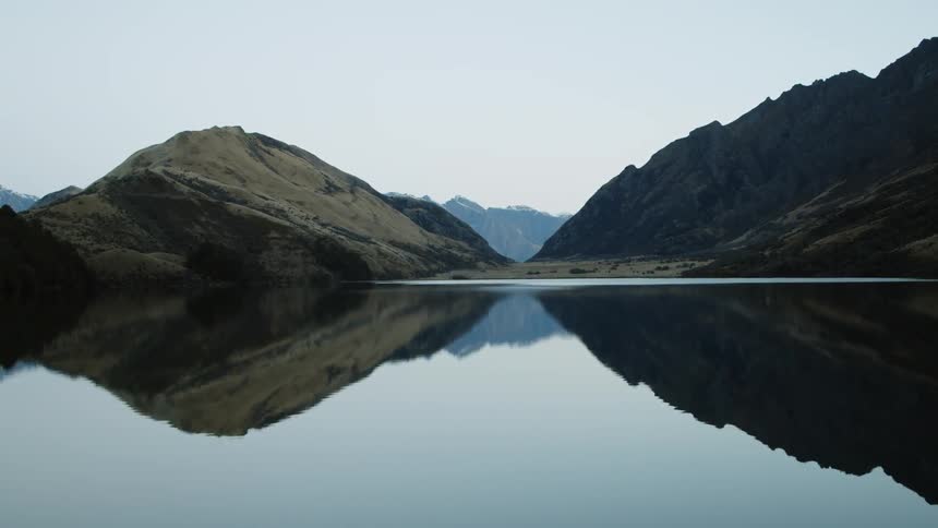 Distant mountains reflected on a body of water during the day