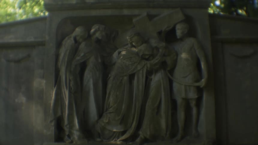 The statue is of a group of people and a cross