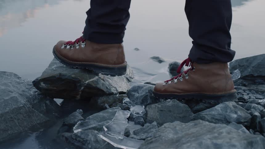 A person stepping on rocks next to water