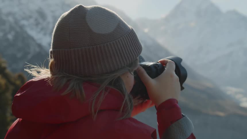 Person takes a picture of mountains with a large camera