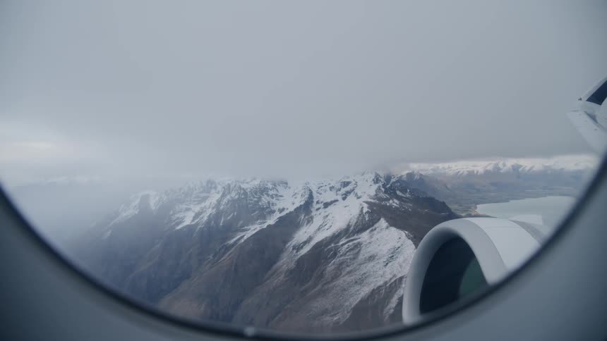 Snowy mountain peaks on cloudy day from airplane window