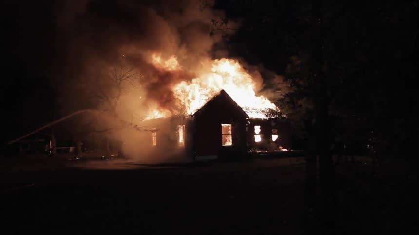 Water being sprayed on a house fire at night