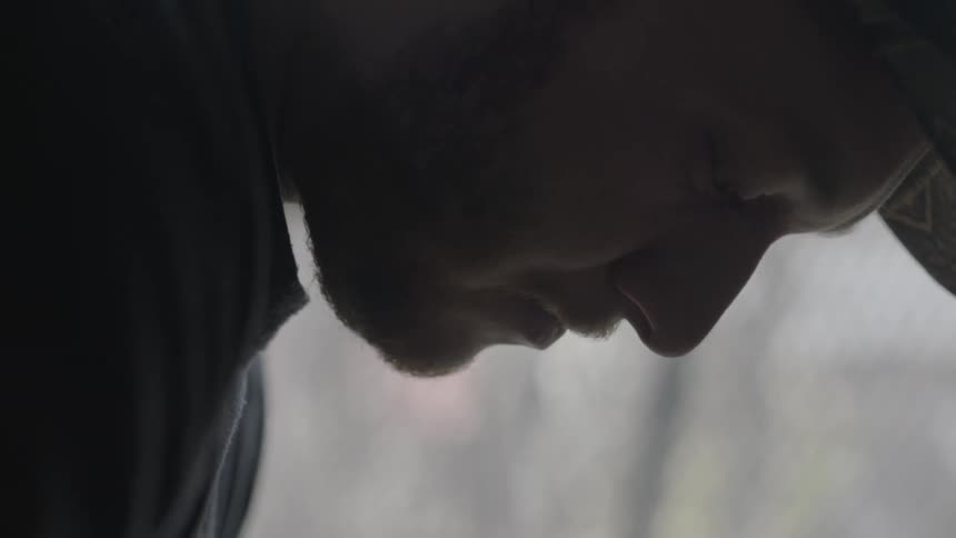 A close shot of a brunette, bearded man wearing a hat