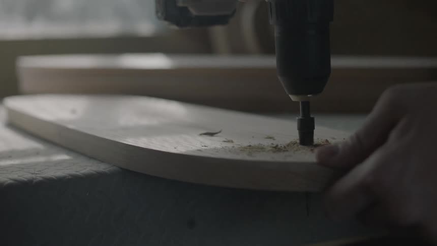 A man is drilling a hole through a piece of wood