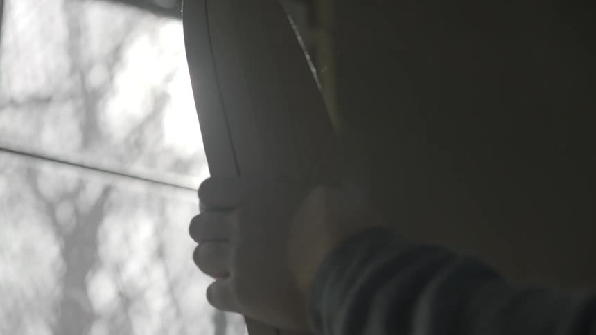 A man compares the size and cut of two wooden boards while standing in front of window