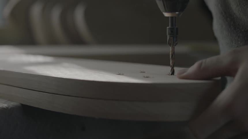 A man is drilling a hole in some wood