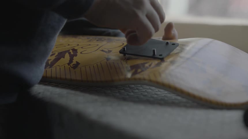 A man is screwing a piece of metal to wood