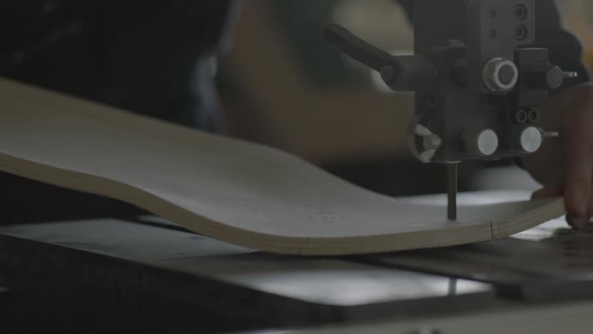 A man uses a table saw to cut a curved piece of wood