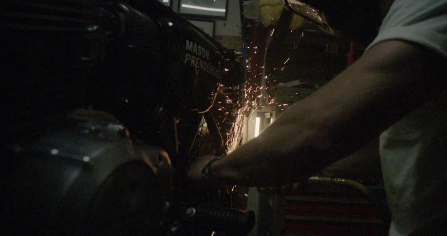 Man using a grinder on his motorcycle with sparks flying around