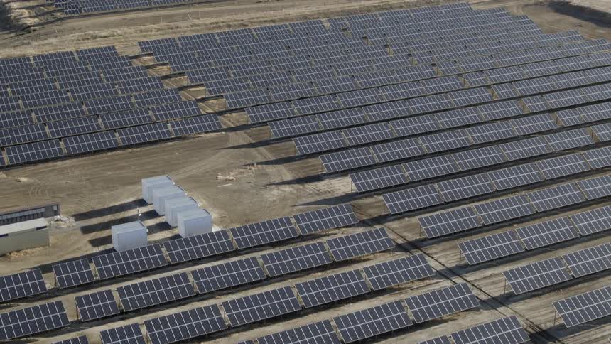 A lot of solar panels that are on a large farm