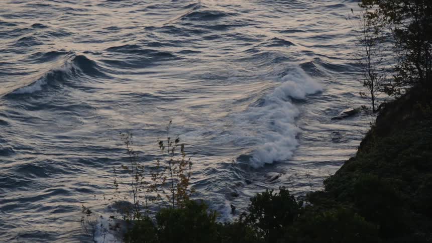 Waves rocking a sea next to a mountain
