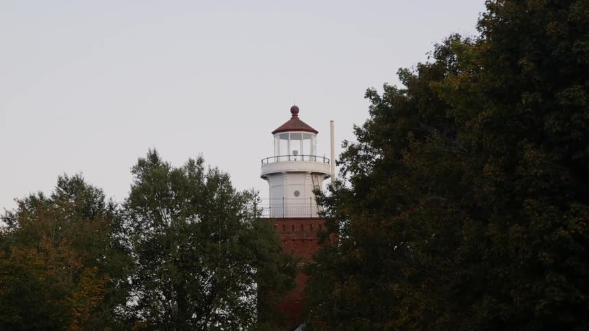 A lighthouse stands surrounded by trees