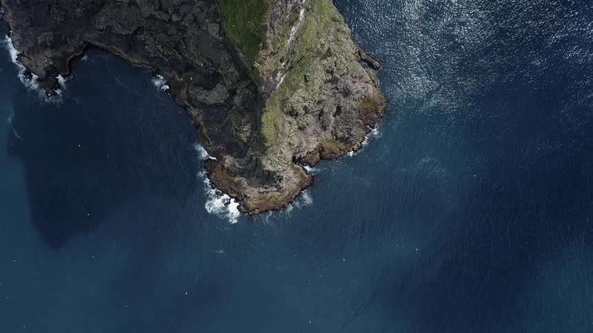 Ocean waves splash around a large cliff