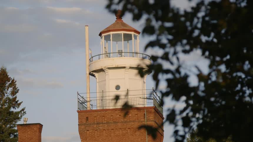 Wind blowing leaves next to a lighthouse