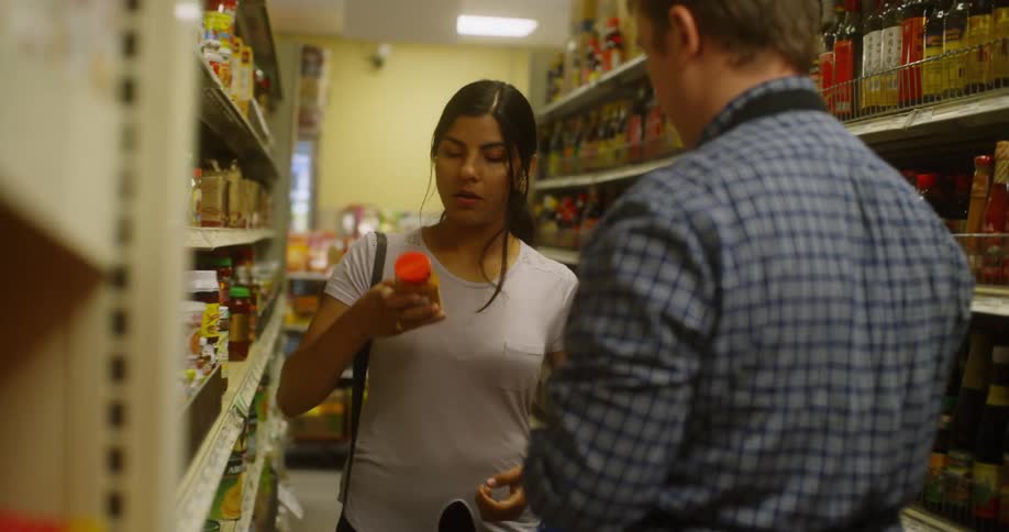 Woman in a grocery aisle asking the help of a grocery worker