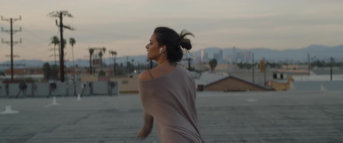 Woman wearing earphones dancing on a rooftop