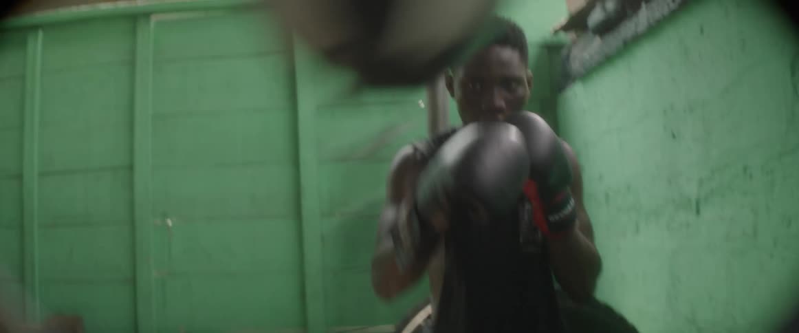 A young man practicing boxing punches an exercise ball repeatedly