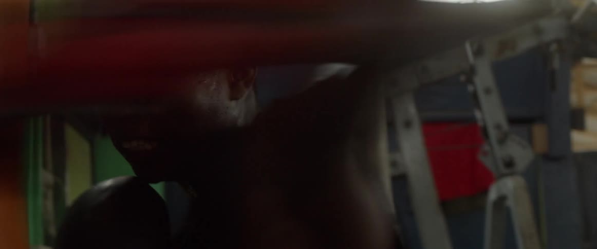 A male fighting walking over to the punching bag and hitting it
