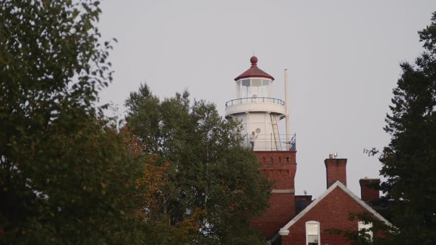 Person walks on the top of a lighthouse surrounded by trees