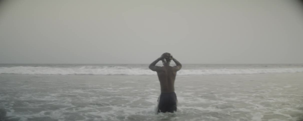 Man on beach walking through waves