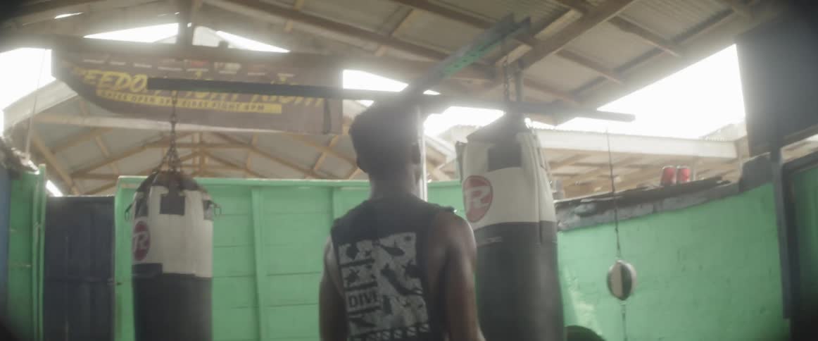 A man wearing boxing gloves moves towards punching bags