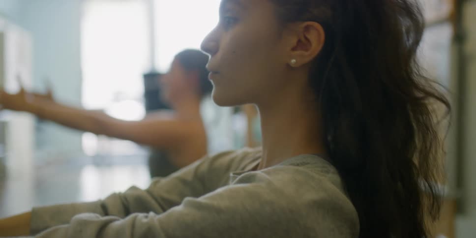 Two women do stretches in a well lit room