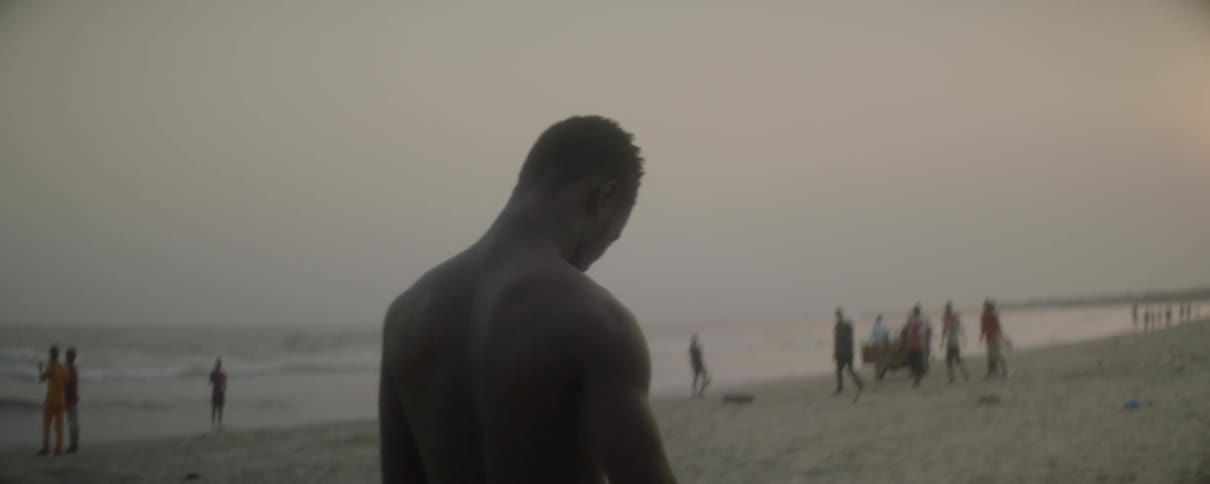 A young man takes his shirt off on a beach