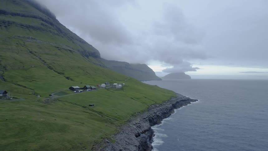 A small village on the edge of a large mountain next to the sea