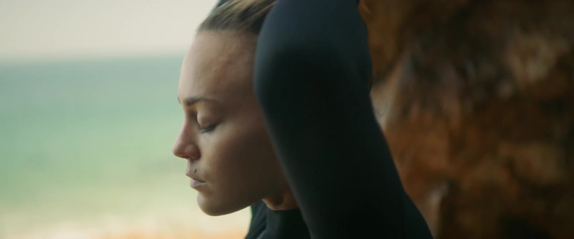 A woman in a wet suit fixes her hair