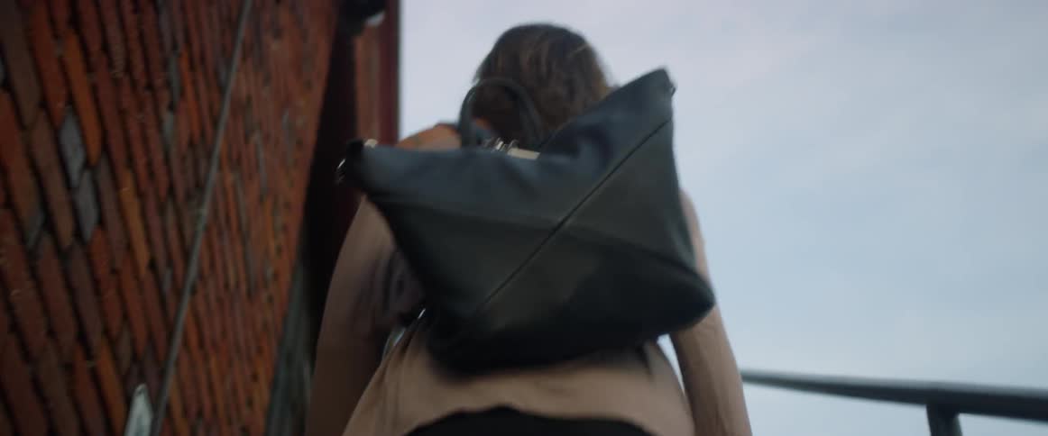 A woman walking up a flight of stairs with a bag on her back