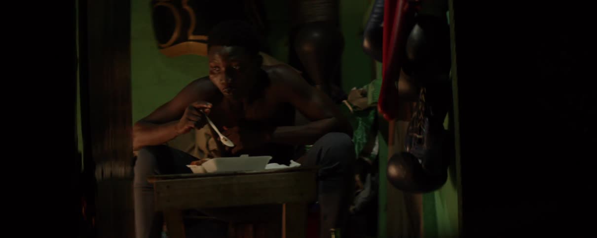 A man eats out of a styrofoam container as he sits alone in the darkness