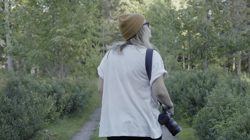 A photographer looking at scenery walking a trail