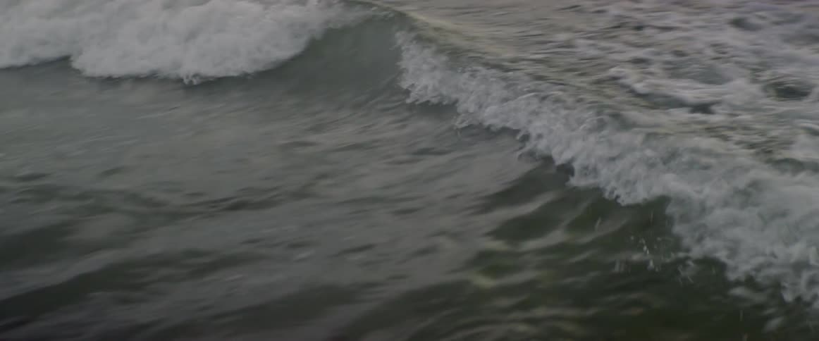 Ocean waves roll towards shore at sunset