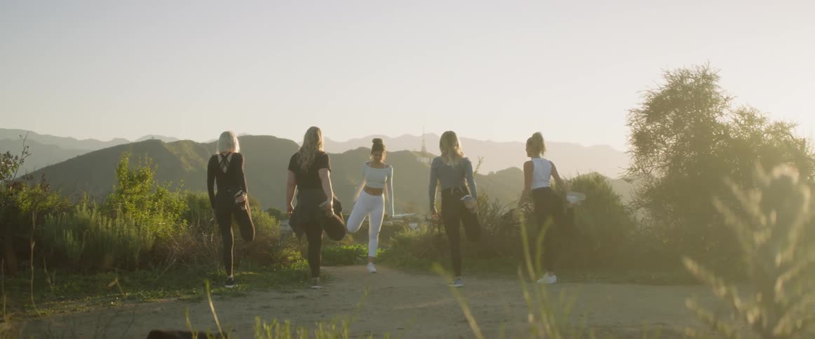 Five women stretch on a road in the mountains