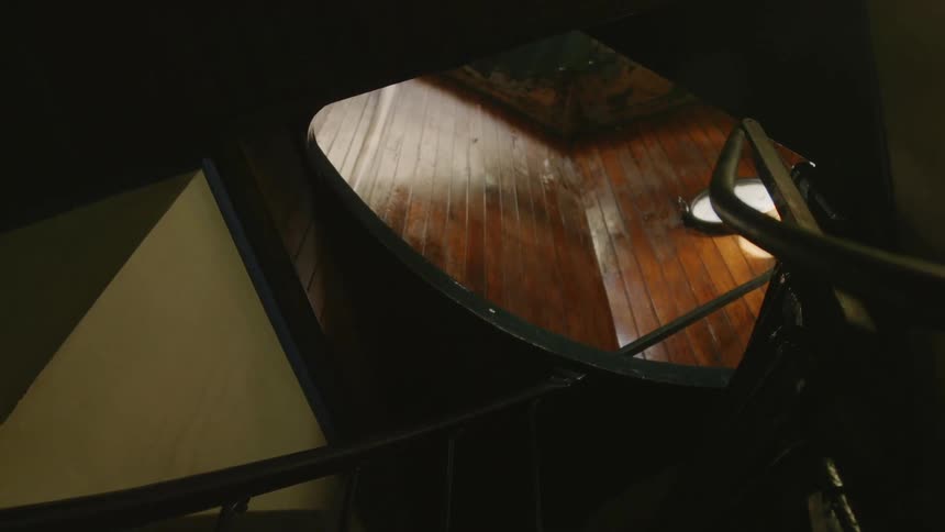 The sun shines through a window above a spiral staircase