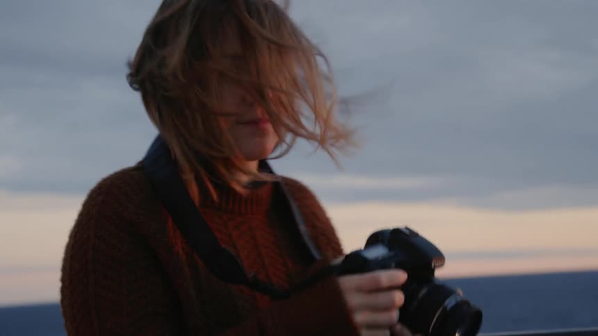 Woman looking at the picture she just took on her camera outdoors on a windy day