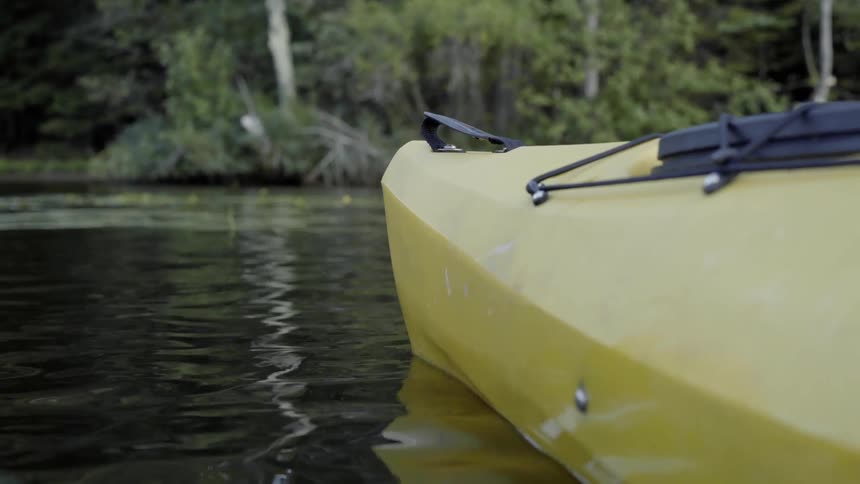 A yellow kayak glides through a calm river