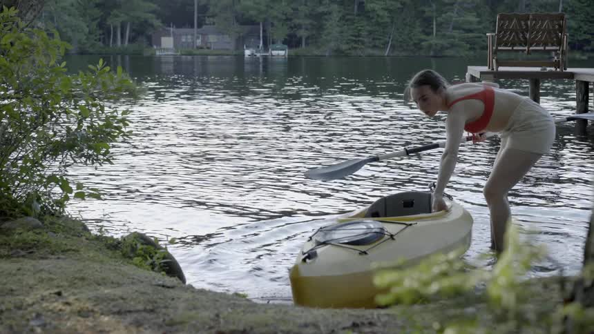 Woman pulls a yellow kayak into a river