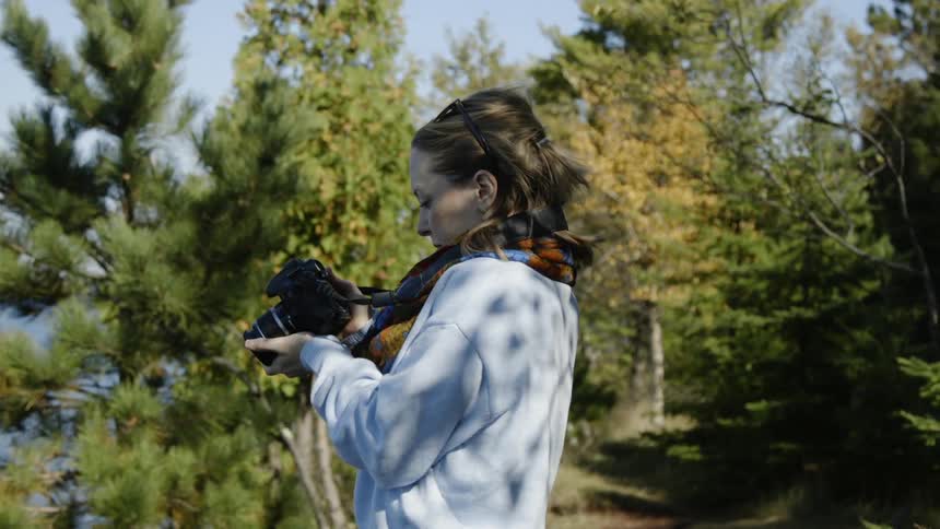A female photographer looking through the camera and glancing at what is captured