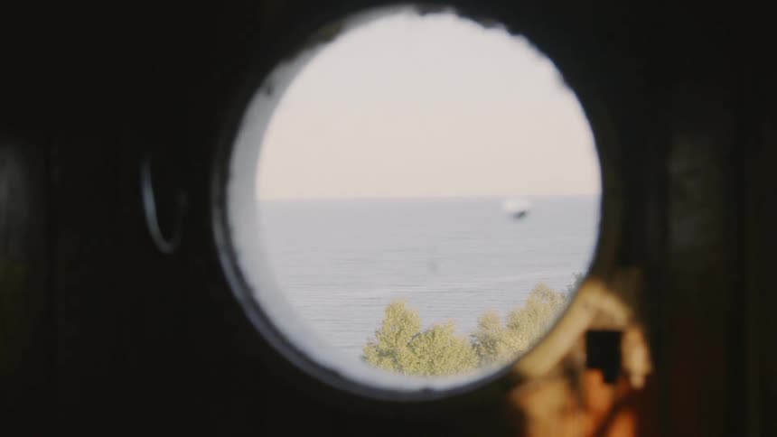 The ocean throughs through a circular hole in a piece of wood