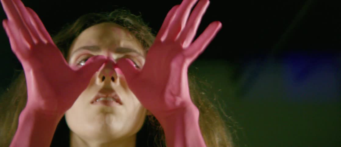 Woman with hands and forearms painted pink covering eyes