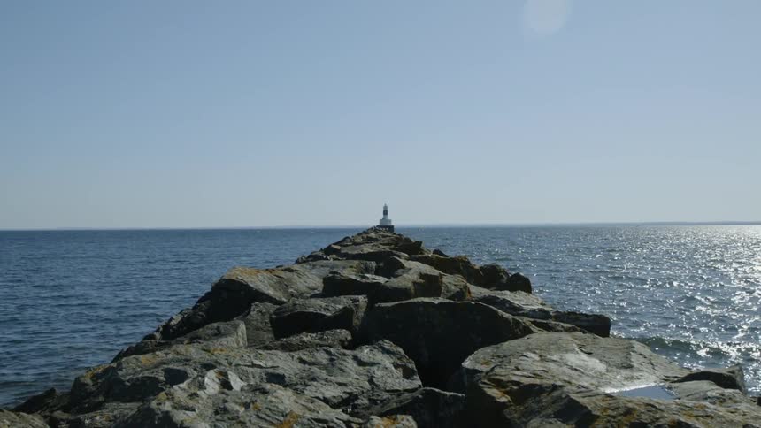 A lighthouse at the end of a rocky pier