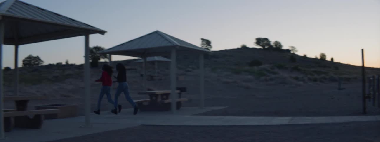Two woman run along a path that's set on the sand