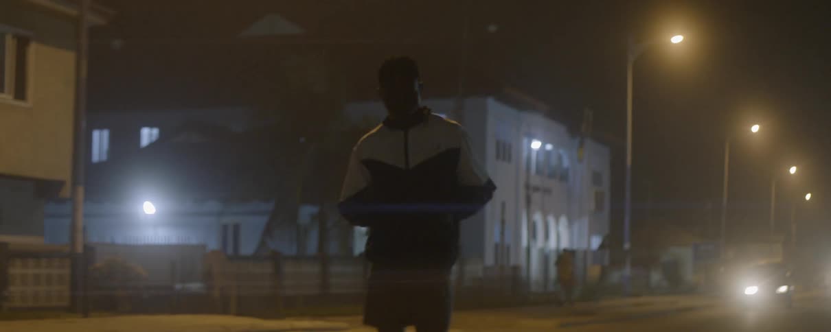 A young man jogs down a city street at night