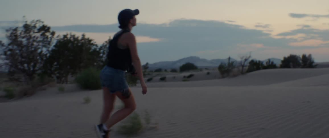 Woman skips across the desert at sunset