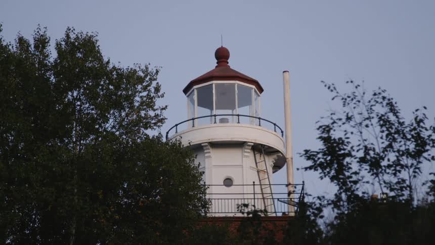 A lighthouse slowly flashing at sunset