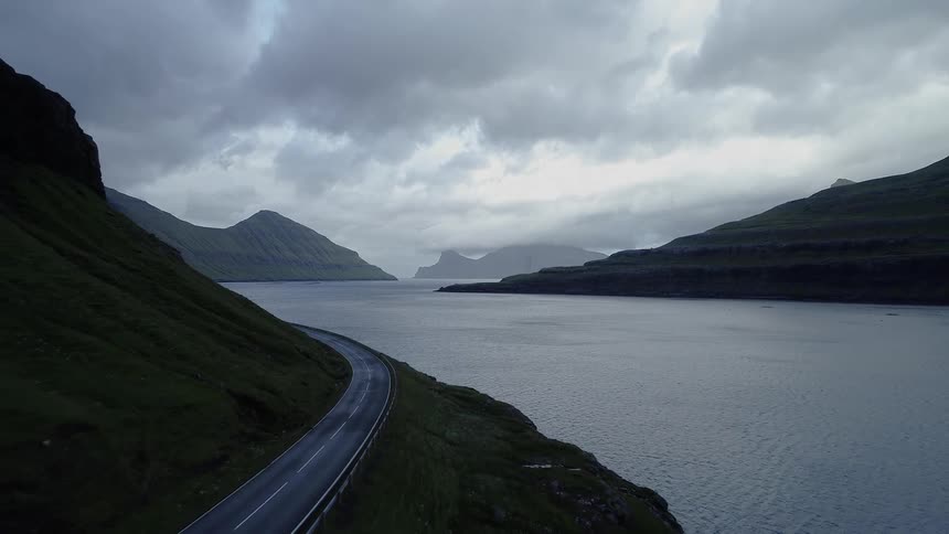 A road alongside a mountain side next to a large river