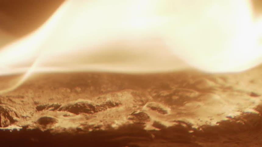 Fire blazes brightly over a bumpy surface