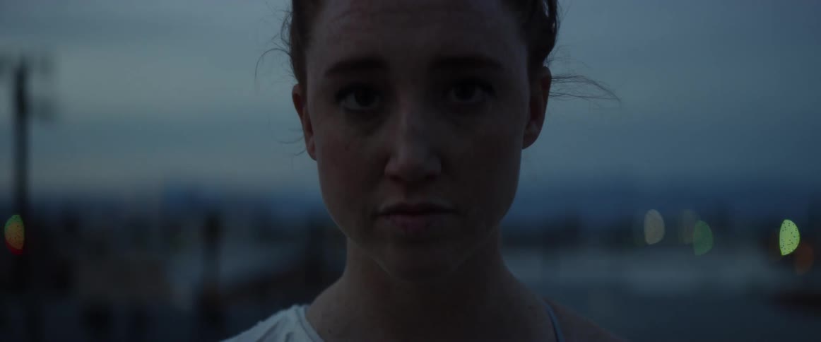 A woman stands outside at dusk smiling